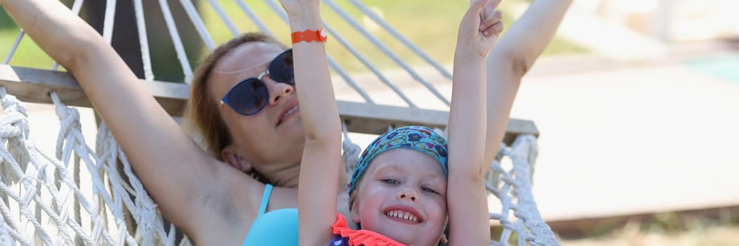 Loving family mom and daughter spend time together in summer hammock. Family happy joyful vacation in summer garden