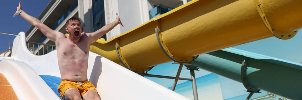 Emotional man screams in horror going down water slide. Testing of opened water park