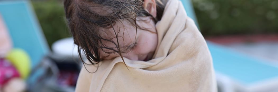 Girl child is wrapped in warm beach towel. Summer children recreation and hypothermia on water