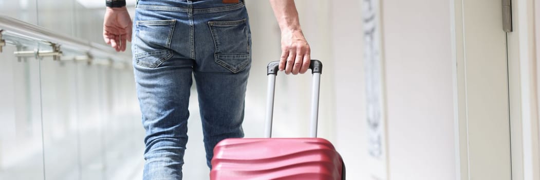 Male tourist pulls suitcase moving to luxury hotel. Booking and check-in at the hotel