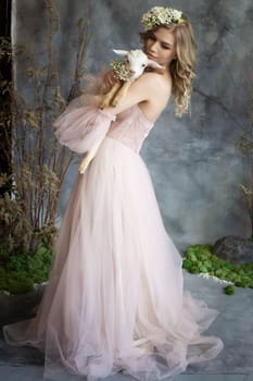 A young blonde woman in an airy pink dress with a white kid. Spring portrait of a woman