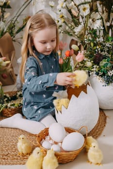 Two girls in a beautiful Easter photo zone with flowers, eggs, chickens and Easter bunnies. Happy Easter holiday