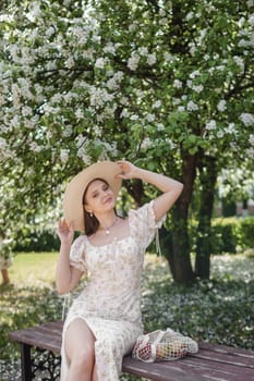 An attractive long-haired woman walks in the spring in the park of blooming apple trees. Spring portrait of a woman