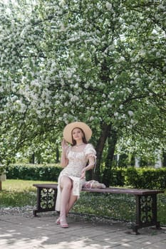 An attractive long-haired woman walks in the spring in the park of blooming apple trees. Spring portrait of a woman