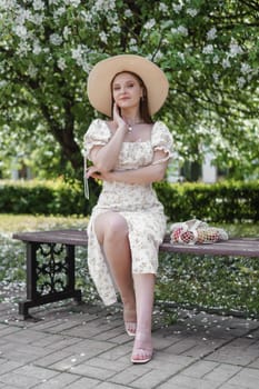 An attractive long-haired woman walks in the spring in the park of blooming apple trees. Spring portrait of a woman