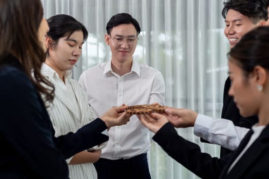 Closeup hand holding wooden gear by businesspeople wearing suit for harmony synergy in office workplace concept. Group of people hand making chain of gears into collective form for unity symbol.