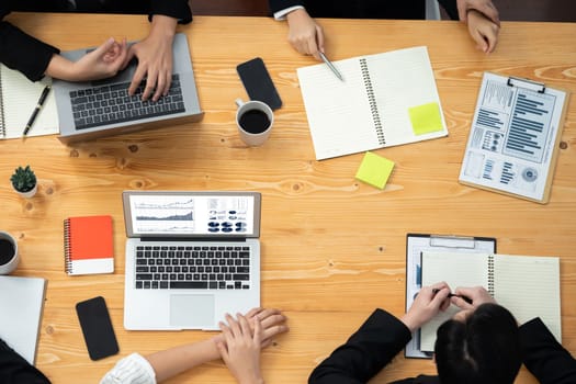 Top-view closeup business team of financial data analysis meeting with business intelligence, report paper and dashboard on laptop. Business group people working together in harmony office.