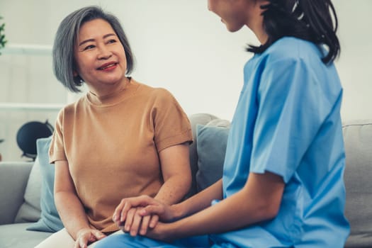 A contented senior woman visited by her personal caregiver and hold each other's hands.