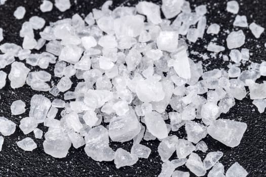 Sea salt on a black background close up macro. Sea salt granules of various sizes