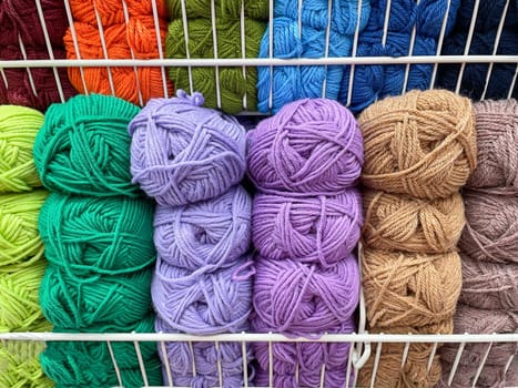 Yarn store display rack of colorful products. Selective focus. Knitting yarn, knitted clothes create coziness.