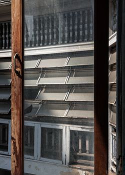 Bangkok, Thailand - Feb 09, 2023 - View through an the old window of ancient old building onto Antique steel awning windows the other side of the building.