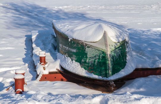 Snow-covered boat on the pier..Inverted boat under the snow..Boat under the snow on the pier..