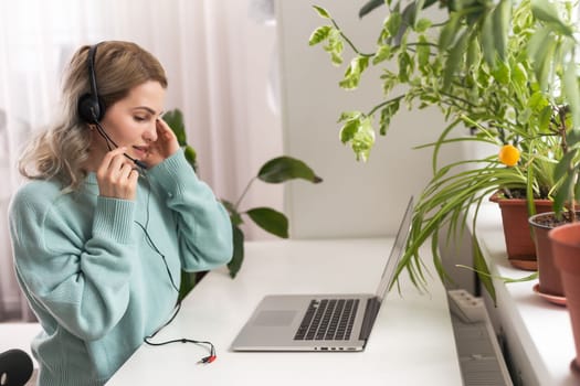 Side view head shot smiling mixed race lady freelancer wearing headset, communicating with client via video computer call. Millennial pleasant professional female tutor giving online language class.