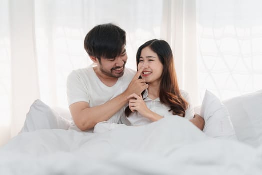 Beautiful asian couple in love and smiling sitting on bed. Romantic moment, relationships, family concept