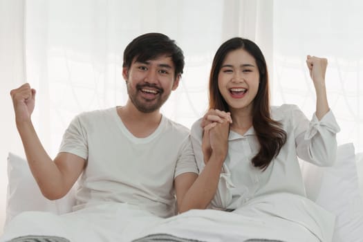 Beautiful asian couple in love and smiling sitting on bed. Romantic moment, relationships, family concept