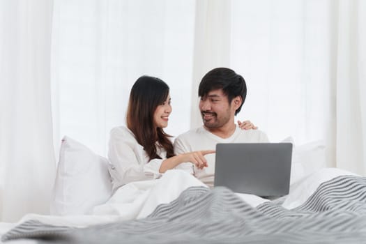 Beautiful asian couple in love and smiling sitting on bed. Romantic moment, relationships, family concept