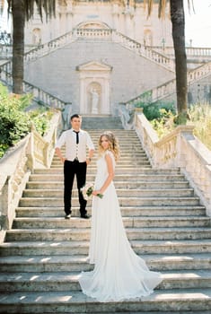 Bride and groom stand on the stone steps of the Church of the Nativity of the Virgin in Prcanj. Montenegro. High quality photo