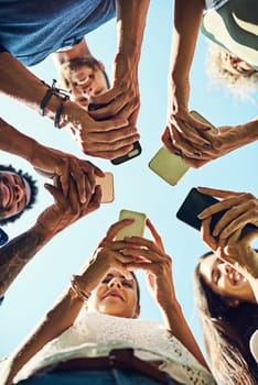 Getting their social connections together. a group of people using their cellphones in synchronicity outdoors