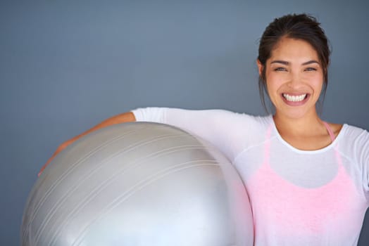 Everyday is a good day to workout. a sporty young woman holding a pilates ball against a grey background