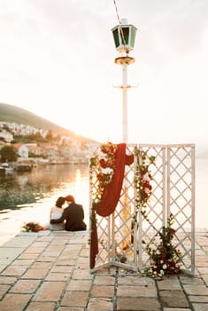 Wedding screen stands on the pier with the bride and groom hugging in the background. High quality photo