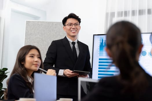 Confidence and asian businessman give presentation on financial analyzed by business intelligence in dashboard report to other people in board room meeting to promote harmony in workplace.