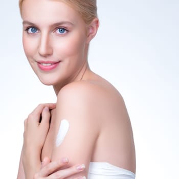 Closeup personable beautiful woman putting skincare moisturizer cream on her arm looking in camera in isolated background as concept for beauty care treatment. Female model applying lotion on her body