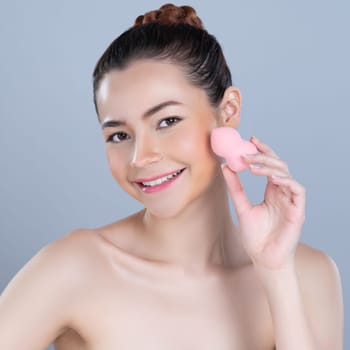 Glamorous beautiful female model applying cushion powder for facial makeup concept. Portrait of flawless perfect cosmetic skin woman put powder puff on her face in isolated background.