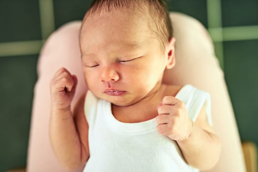 He might grow up to be a champion boxer. a tired little baby boy sleeping with his eyes closed while his mother holds him in her hands at home