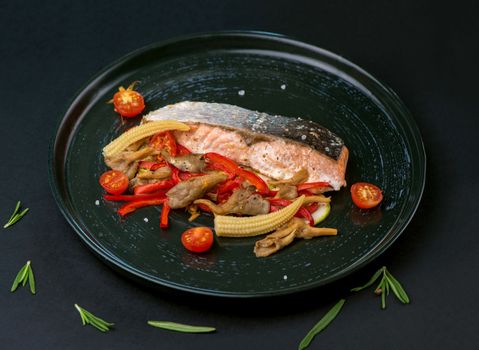 Fried salmon steak with vegetables on wooden table