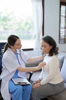 Portrait of a female doctor using a stethoscope to check the pulse of an elderly patient