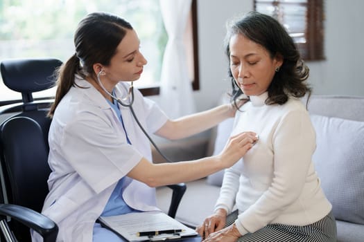 Portrait of a female doctor using a stethoscope to check the pulse of an elderly patient