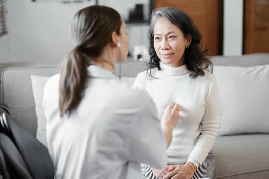 Portrait of a female doctor using a stethoscope to check the pulse of an elderly patient