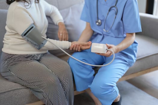 Portrait of female doctor measuring patient's blood pressure before treatment