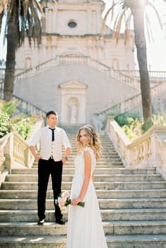 Bride and groom stand on the steps of the Church of the Nativity of the Virgin. Prcanj, Montenegro. High quality photo