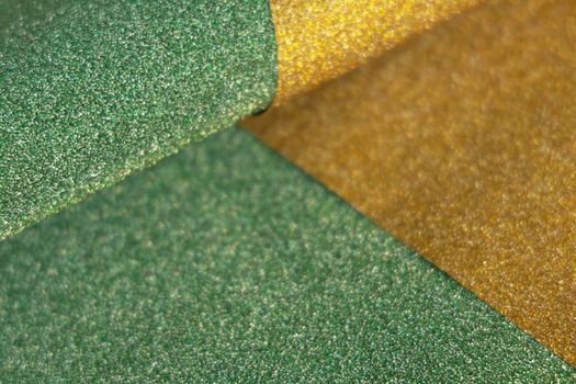 Golden and green wave shiny glitter paper texture. Shining luxurious fabric. Glimmering light green golden color, christmas background