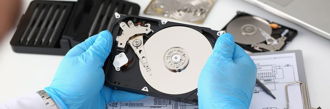 Technician repairs computer hard drive from motherboard. Hard drive diagnostic services concept