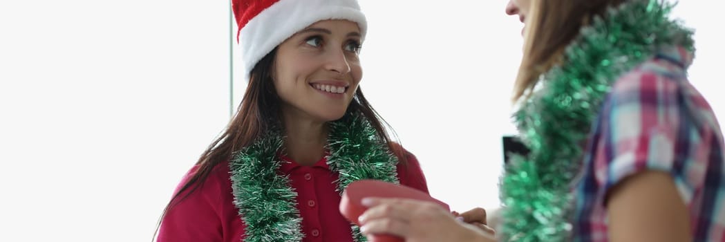 Young woman gives friend a beautiful wrapped present for new year and christmas. People celebrate and celebrate each other