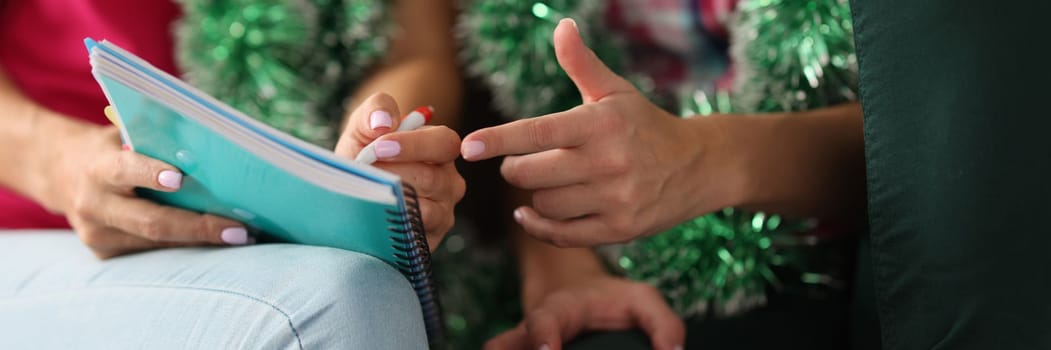 Women hands with a pen and notepad make shopping list for celebration of christmas and new year. Party and festival planning