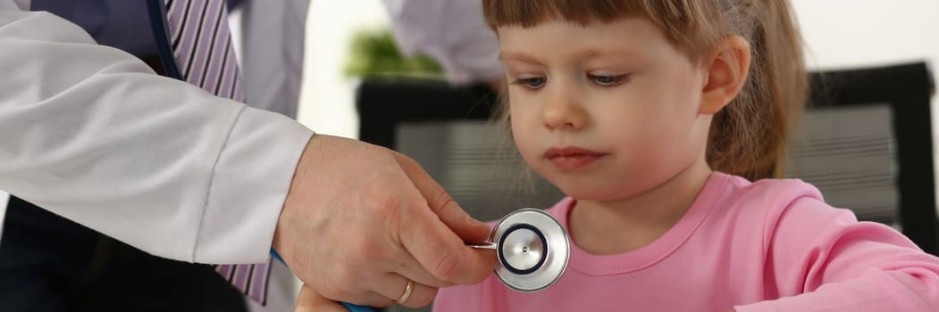 Hands of pediatrician doctor examining small child with stethoscope. Pediatrics and medicine healthcare concept