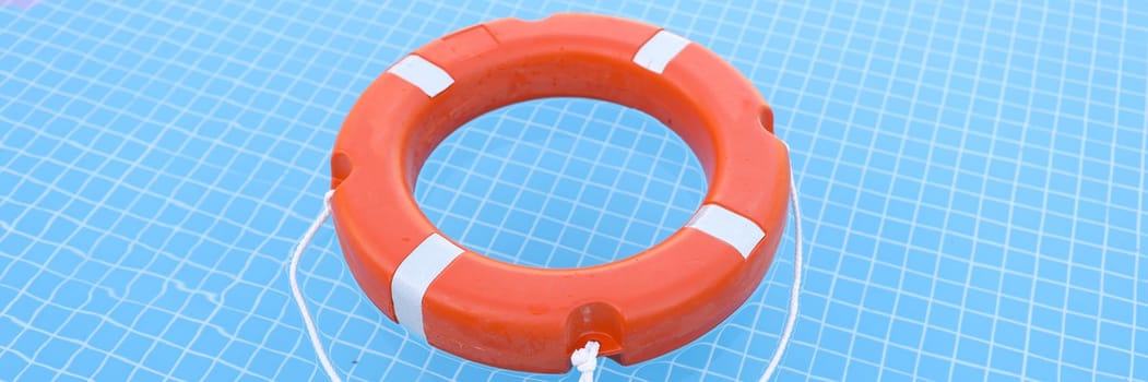 Lifebuoy on blue water with sun glare. Water safety concept