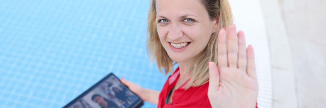 Happy smiling female boss holding online meeting on tablet by pool. Remote work control and telework for freelancers