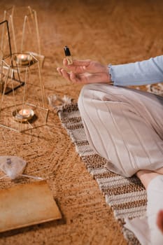 A woman is sitting in a lotus position with scented candles in her hands in the gym.