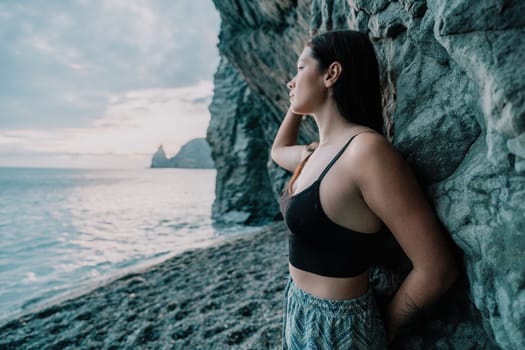 Portrait of cheerful female climber ascending a rock. The athlete girl trains in nature. Woman overcomes difficult climbing route.