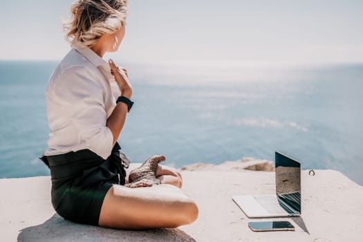 Happy girl doing yoga with laptop working at the beach. beautiful and calm business woman sitting with a laptop in a summer cafe in the lotus position meditating and relaxing. freelance girl remote work beach paradise