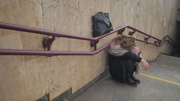 A young girl crying by the stairs in the subway