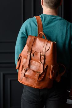 Orange leather oldfashioned backpack on a mans back. indoors