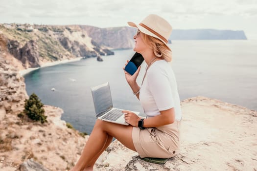 Digital nomad, Business woman working on laptop by the sea. Pretty lady typing on computer by the sea at sunset, makes a business transaction online from a distance. Freelance remote work on vacation