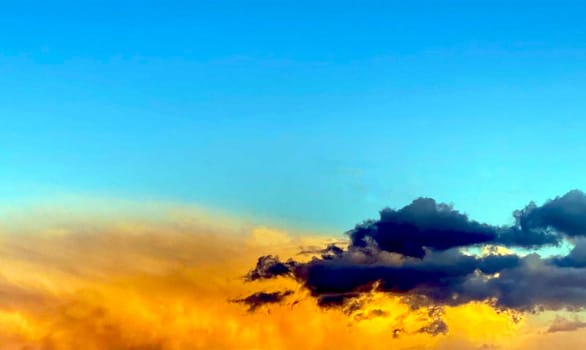 Anxious sunset. Gray and orange clouds in blue sky. High quality photo