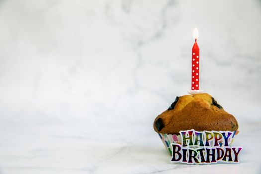 Birthday cupcake with and one red birthday cake candle on a white background with copyspace to side, Happy Birthday, party concept close up