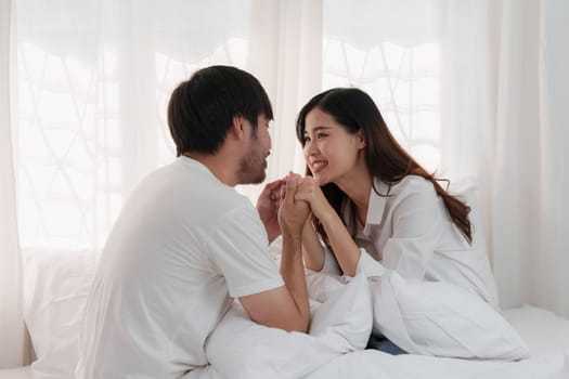 Beautiful asian couple in love and smiling sitting on bed. Romantic moment, relationships, family concept